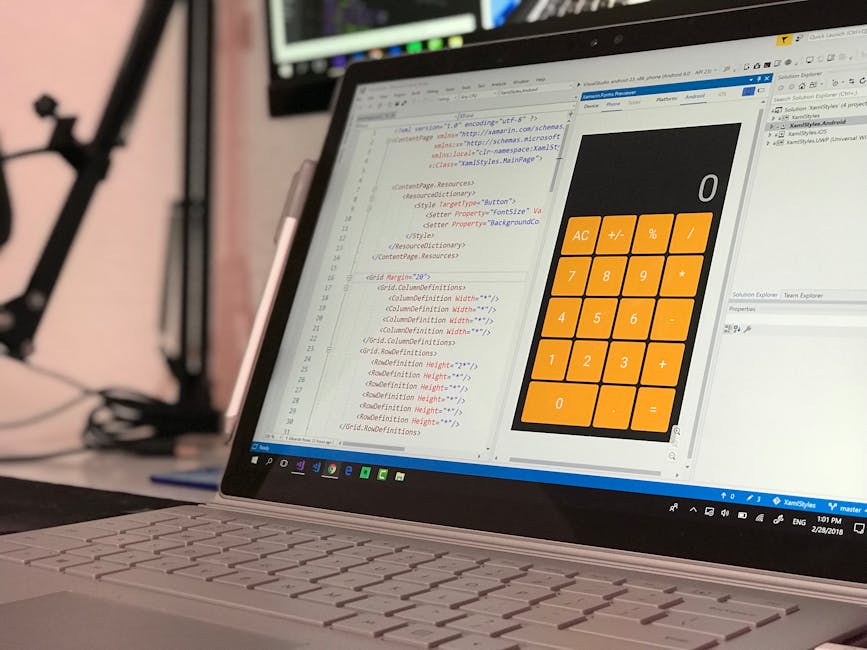 A close-up of a silver laptop displaying a coding interface with text in various colors on the left side, and a large, orange calculator app on the right side. The coding window shows lines of HTML an